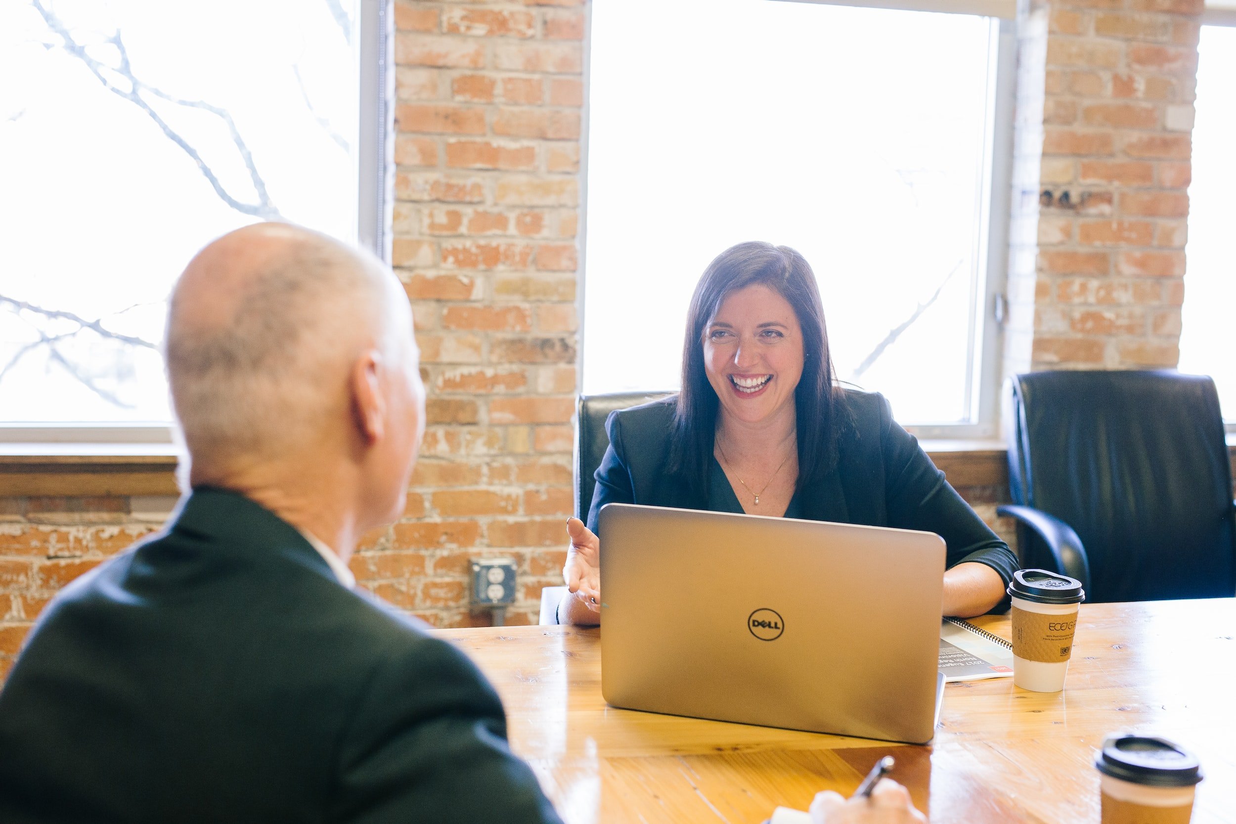 Woman at laptop smiling at man in conversation