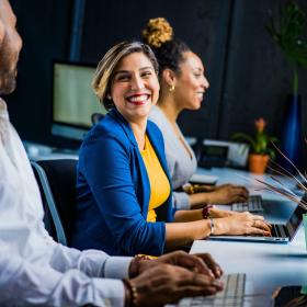 Woman on a laptop smiling at coworker