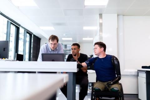 Man in wheelchair reviewing laptop with team